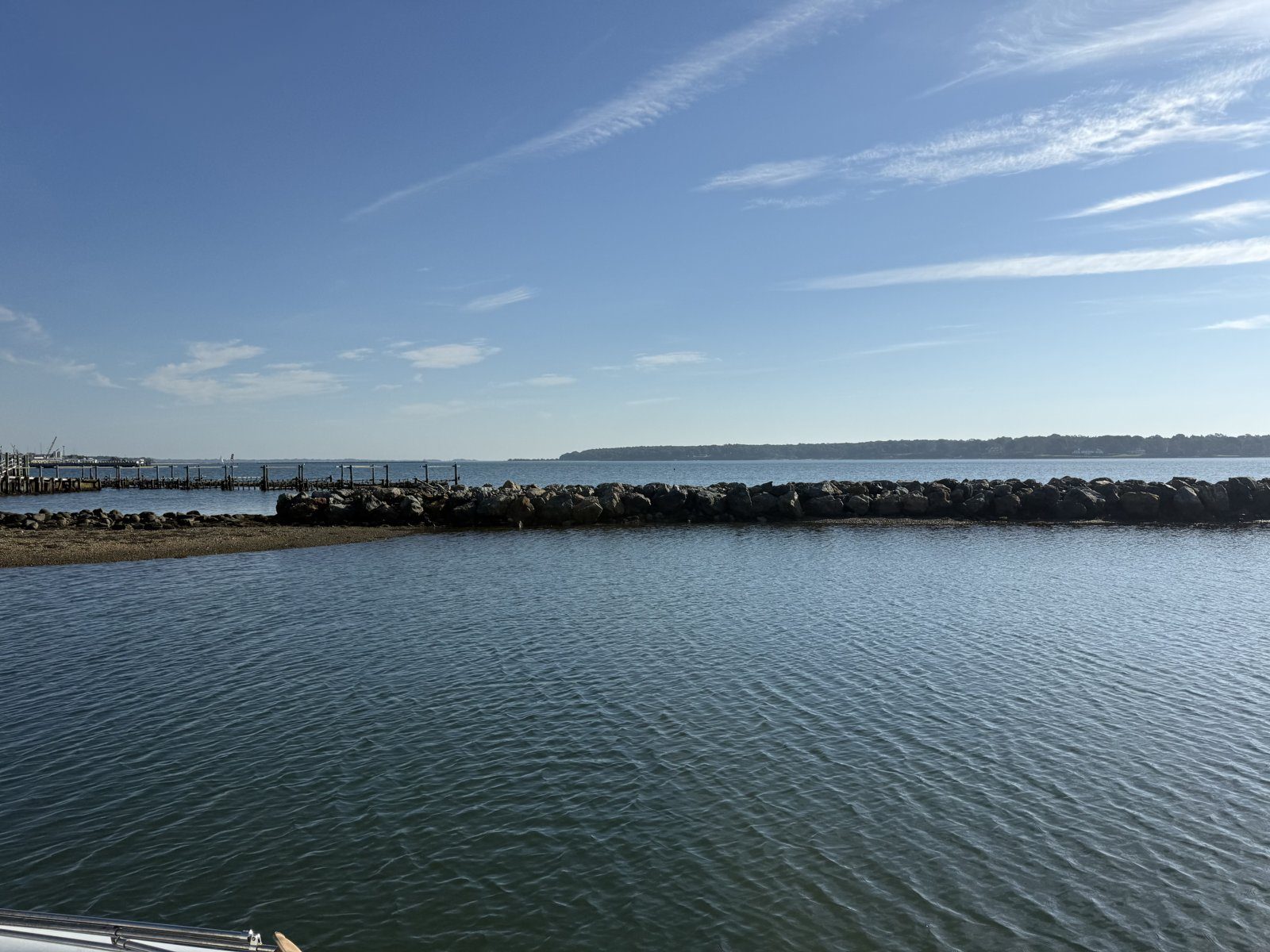 The rebuilt rock jetty at Widow's Hole seen across calm water, October 2026