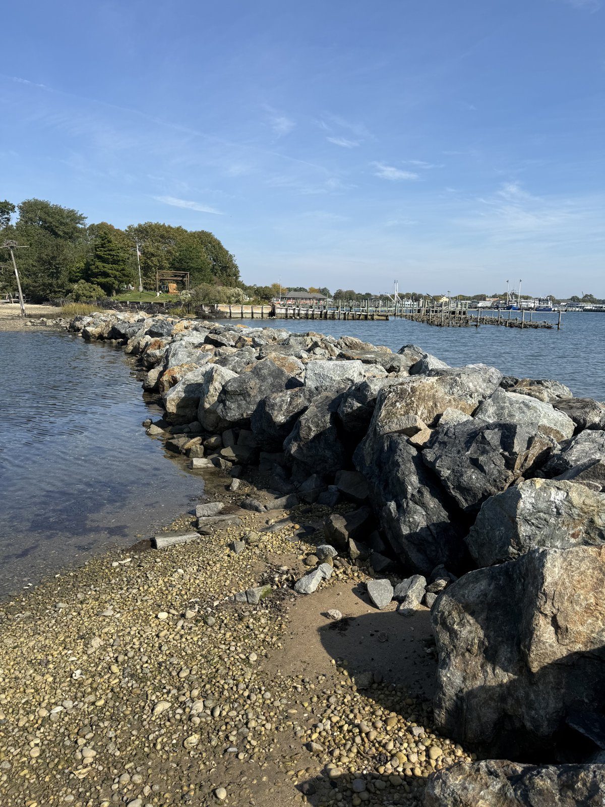 The rebuilt jetty from the beach, with village docks and stake moorings beyond, October 2026