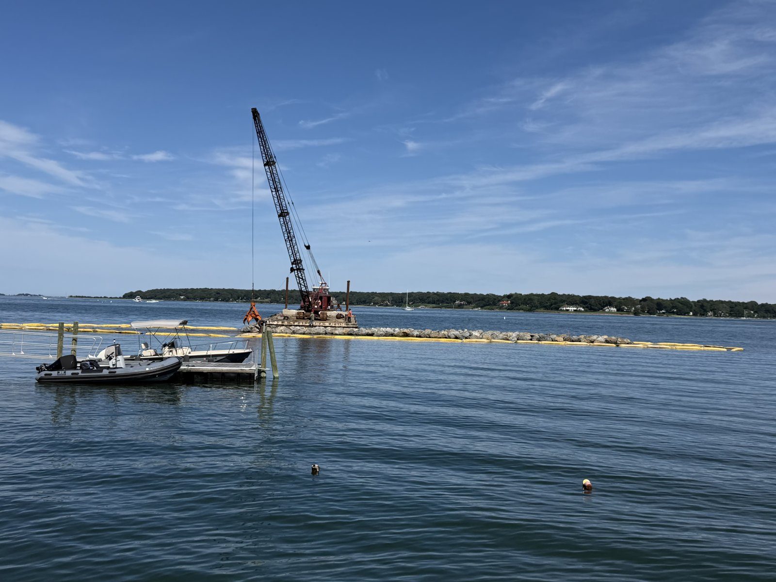 Barge and crane working along the jetty line with turbidity boom, August 2026